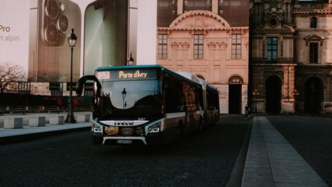 Bus on a cobblestone plaza with ornate historic buildings; route 27 Porte d’Ivry shown on display.