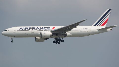 Air France passenger jet with landing gear extended in flight against a cloudy sky