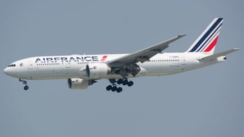 Air France wide-body airliner with landing gear extended, approaching a runway in steady flight against a clear sky