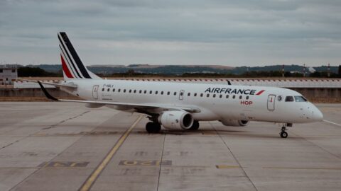 Air France passenger jet parked on the tarmac with a striped tail under a cloudy sky.