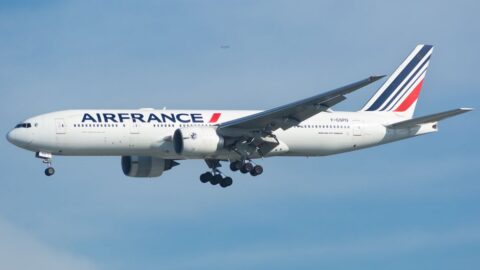 Air France passenger jet with landing gear down in clear blue sky.