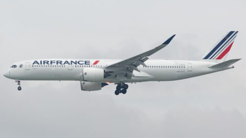 Air France commercial jet with landing gear down, approaching for landing in a cloudy sky.